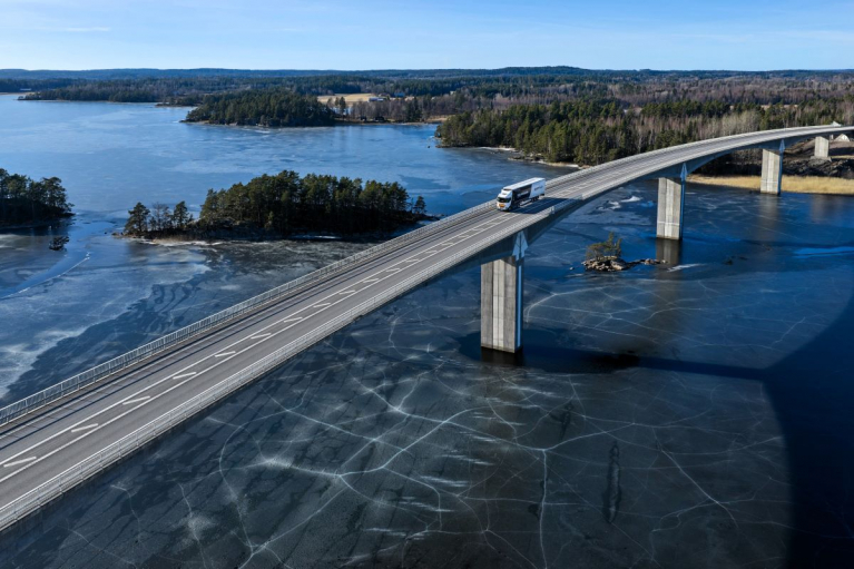 A Scania battery-electric truck driving across a bridge, representing the company’s shift towards a sustainable transport system.