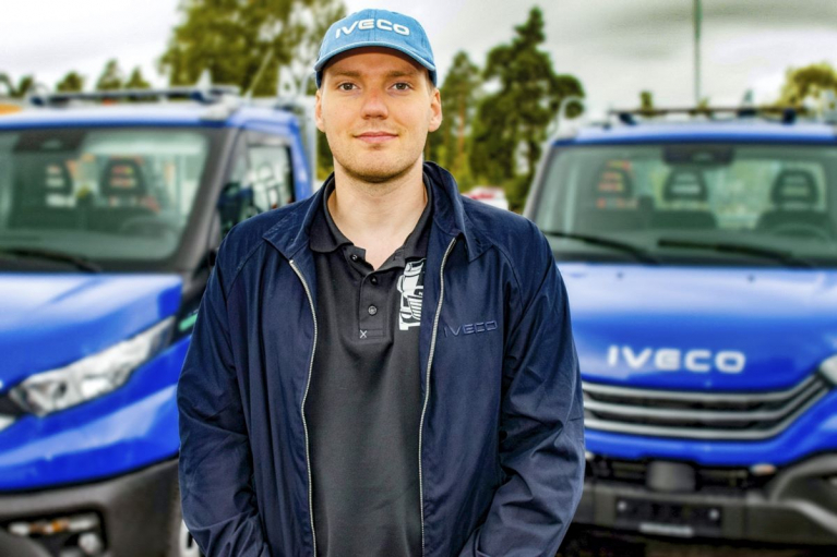 Jesse Saurén seisoo kahden sinisen IVECO-hyötyajoneuvon edessä.