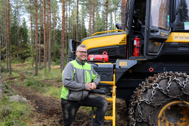 Hakkuuhaukat Oy:n yrittäjä Kai Kotola seisoo metsäkoneen vieressä metsätyömaalla.