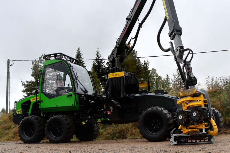 Vihreä kahdeksanpyöräinen Jarcrac CW60 -yhdistelmäkone sivulta kuvattuna Kesla-harvesteripää puomin varassa.