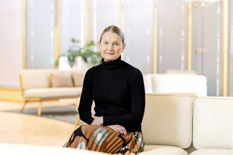 Maija Pohjakallio istuu vaalealla sohvalla toimistoympäristössä.