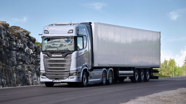 Hopeanvärinen Scania S -sarjan kuorma-auto ja umpikori¬puoliperävaunu maantiellä kallioleikkauksen vieressä.