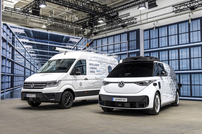 Valkoinen Volkswagen Crafter ILS vasemmalla ja katolle asennetulla laitteistolla varustettu ID. Buzz AD oikealla näyttelytilassa.