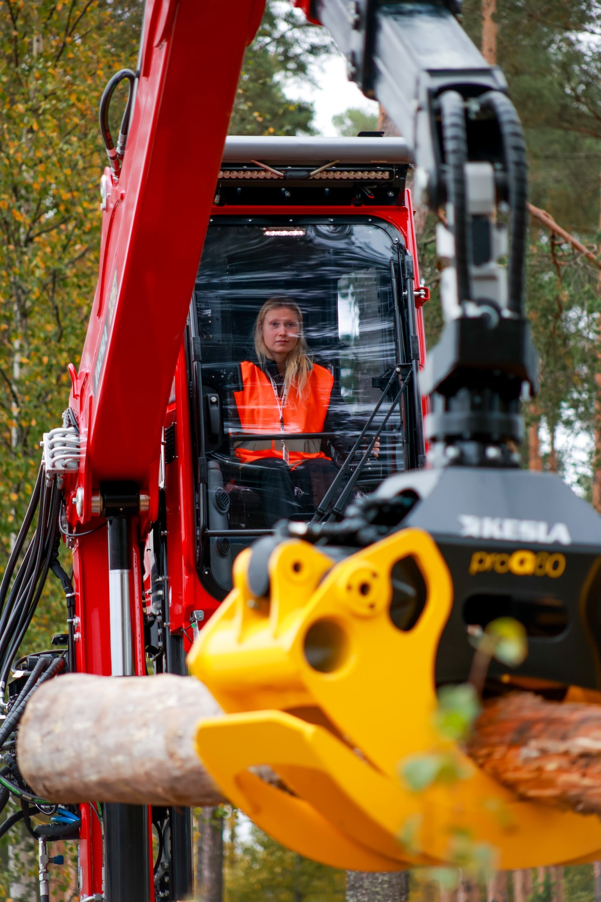 Ampumahiihtäjä Inka Hämäläinen Keslan koneen ohjaamossa metsäympäristössä.