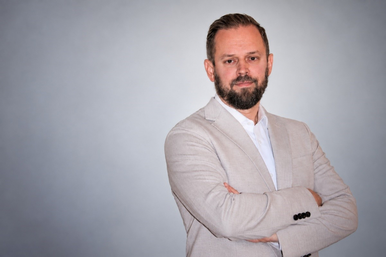 Keslan myynti- ja jälkimarkkinointijohtajaksi nimitetty Tuomo Salo vaaleassa pikkutakissa harmaata taustaa vasten.