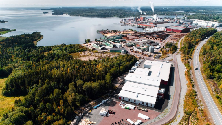 Aerial view of Stora Enso’s Gruvön sawmill and CLT production site in Sweden, with production buildings and timber storage areas beside a lake.