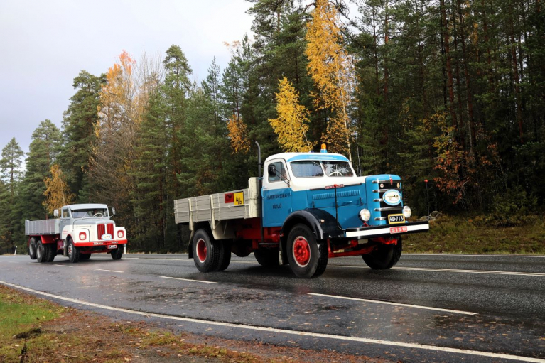 Sinivalkoinen Sisu ja sen perässä ajava Scania-Vabis-lavakuorma-auto syksyisellä maantiellä.