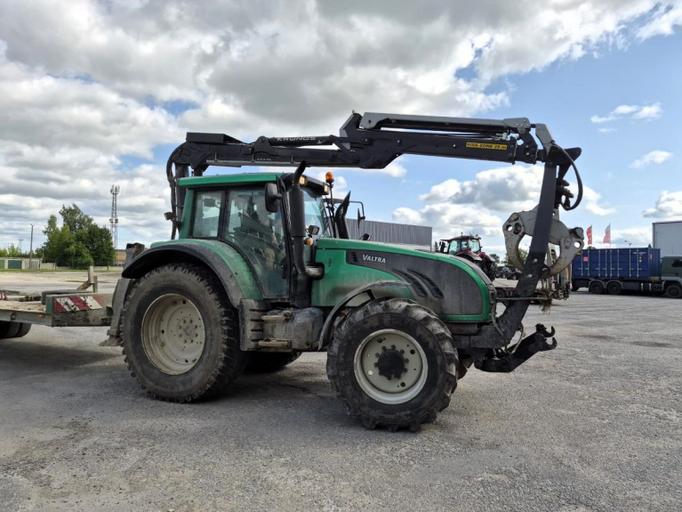 Vihreä Valtra T202 -traktori Tauren pihalla. Kronoksen kuormaimen puomi ulottuu ohjaamon yli, ja koura on traktorin edessä.