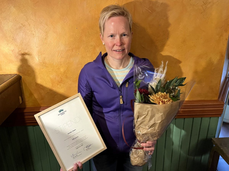 Annika Vaara pitelee kehystettyä Metsämiesten Säätiön stipenditodistusta ja kukkakimppua.