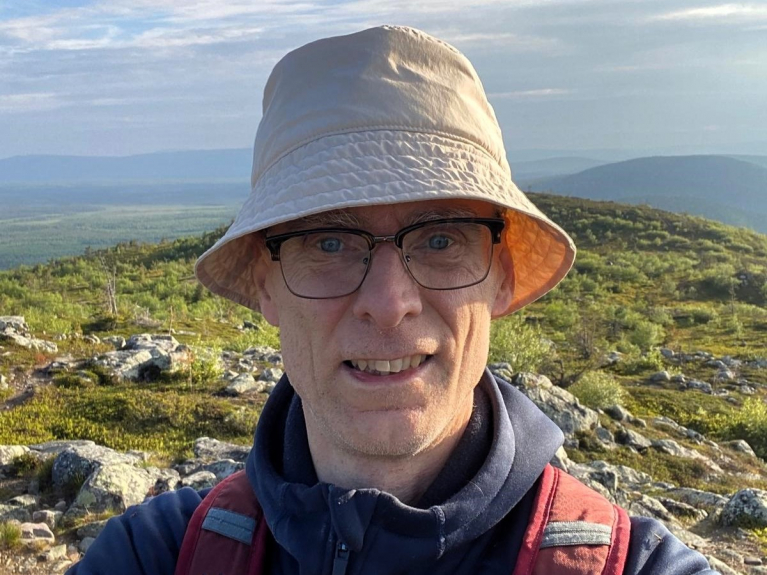 Tuomas Pöysti vaellushattu päässään ja reppu selässään kivikkoisessa tunturimaisemassa.
