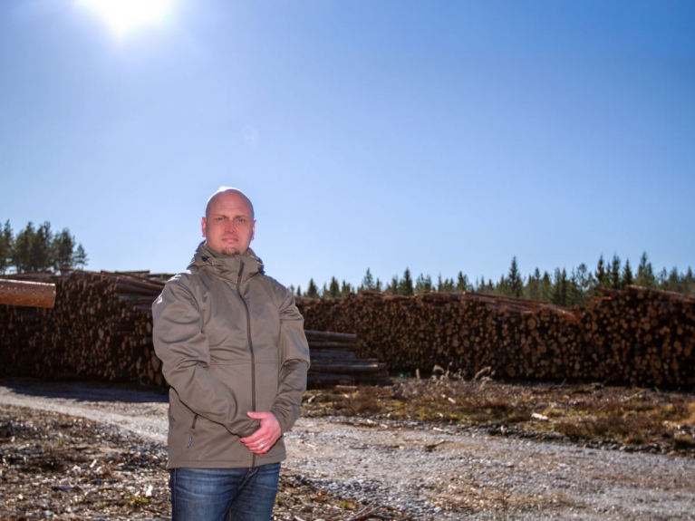 Metsätrans-lehden päätoimittaja Tero Nurmi seisoo puutavarapinojen edustalla.