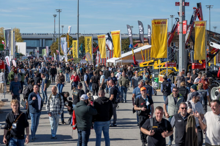 Visitors walking between forestry machinery displays and exhibitor stands in the outdoor exhibition area at INTERFORST 2026 in Munich.