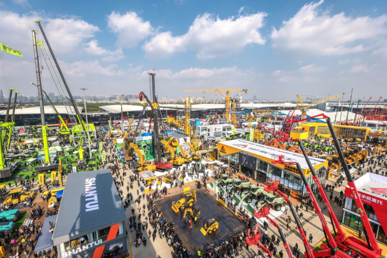 Elevated view of the outdoor exhibition area at bauma CHINA 2024 in Shanghai, with cranes, construction machinery and crowds of visitors.