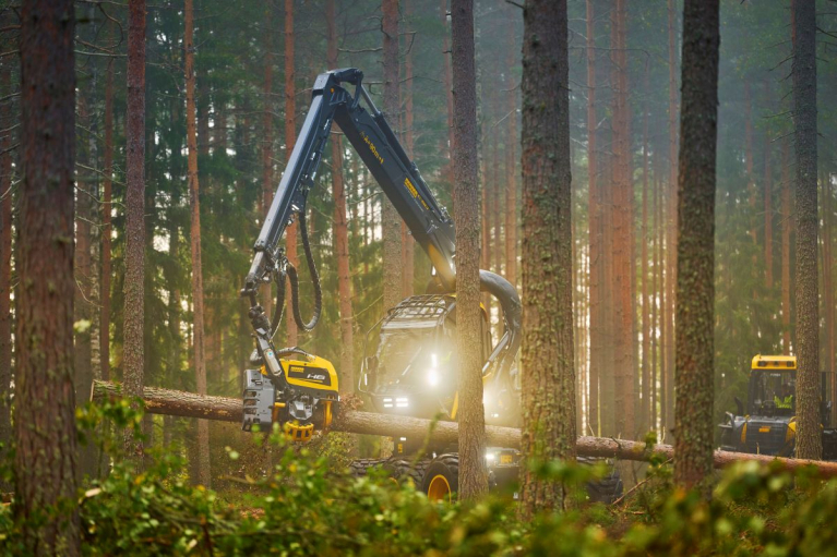 Ponssen harvesteri käsittelee puunrunkoa havumetsässä. Taustalla näkyy toinen metsäkone.