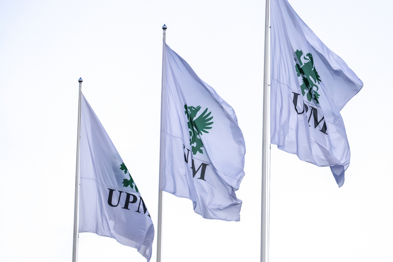 Three white UPM flags flying on flagpoles.